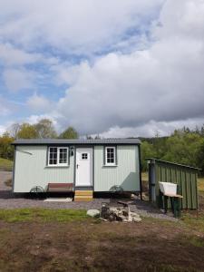 una casita verde y blanca en un campo en Wee Highland Hideaway Hut, en Dalmally