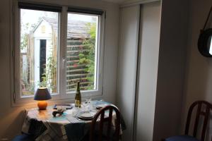 una mesa con una botella de vino y una ventana en Petit studio CYPRÈS du BOIS en Noirmoutier-en-l'lle