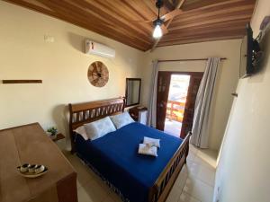 Pousada da Brisa في إيتانهايم: غرفة نوم بسرير ازرق وطاولة