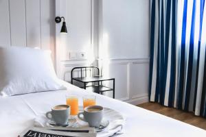 a bed with two cups of coffee and two glasses of orange juice at Hotel & Restaurant Marina Palamós in Palamós