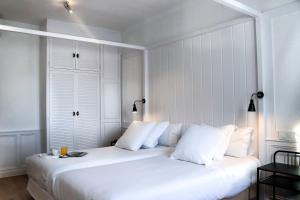 1 dormitorio blanco con 1 cama grande con almohadas blancas en Hotel Marina, en Palamós