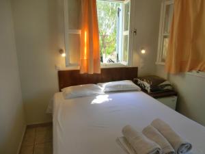 1 dormitorio con 1 cama blanca y 2 toallas en Santorini Camping/Rooms, en Fira