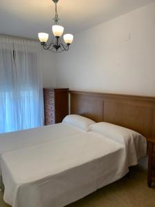 1 dormitorio con 1 cama blanca grande con lámpara de araña en Apartamento dúplex en el centro de Huesca en Huesca