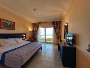 a bedroom with a bed and a television and a window at Palm Beach Resort Families and Couples only in Hurghada