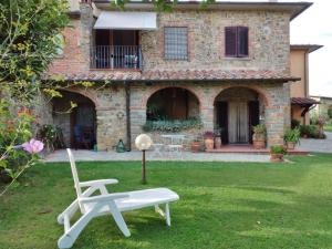 einen Garten mit einem Stuhl, einem Tisch und einem Haus in der Unterkunft B&B L'Oliveto in Lucignano
