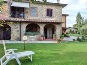 een stenen huis met een witte bank in de tuin bij B&B L'Oliveto in Lucignano
