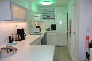 une cuisine avec des comptoirs blancs et des appareils électroménagers blancs dans l'établissement Superior Citycottage Kristiansand, à Kristiansand