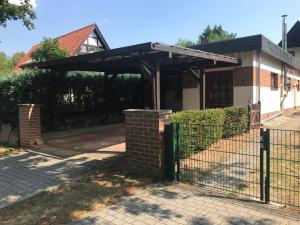 a wooden pergola on a house with a fence at Ferienhaus an den Moorwiesen in Bad Saarow