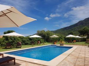 a swimming pool with chairs and umbrellas at Sa Plana Petit Hotel in Estellencs