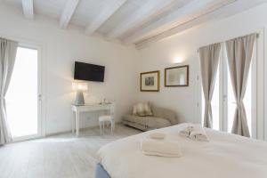 - une chambre blanche avec un lit et un canapé dans l'établissement Affittacamere Ortygia Inn Rooms con Terrazza sul Mare e Jacuzzi, à Syracuse
