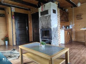 a living room with a stone fireplace and a table at Bieszczadzka Chatka in Smerek