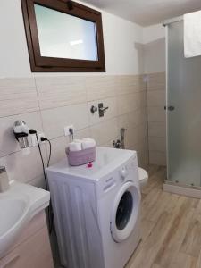 a white washing machine in a bathroom with a sink at La casa del melograno in Marsala