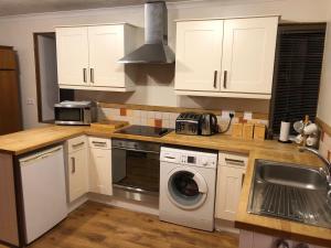 a kitchen with white cabinets and a washing machine at Spacious comfortable flat in Scalloway, Shetland. in Scalloway