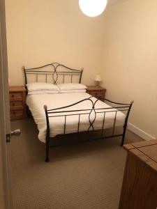 a bedroom with a bed with white sheets and a lamp at Spacious comfortable flat in Scalloway, Shetland. in Scalloway