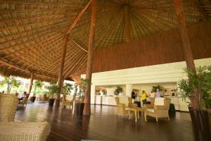 a restaurant with a large straw roof and tables and chairs at Akumal Bay Beach & Wellness Resort in Akumal