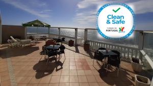 a balcony with tables and chairs and a sign that says clean and safe at Albergaria Pedra D'Ouro in São Pedro de Moel