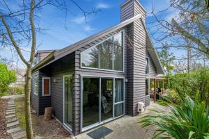 una casa con grandes ventanas de cristal en un lateral en A Hop, Skip & Jump to The Lake, en Taupo