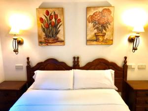 a bedroom with a bed and three paintings on the wall at Hostal Posada La Panadera in Sepúlveda