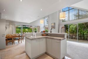 a kitchen with white cabinets and a dining room at A Hop, Skip & Jump to The Lake in Taupo