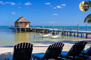 two chairs and a hammock on a beach with a dock at Portofino Beach Resort-An Authentic Island Escape! in San Pedro