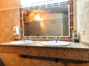a bathroom with two sinks and a large mirror at Hostal Posada La Panadera in Sepúlveda