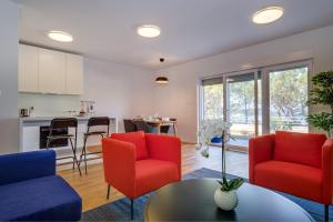 an open living room with red chairs and a kitchen at Dea2 in Mali Lošinj