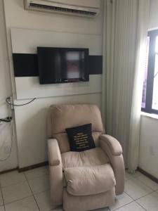 un soggiorno con sedia e TV a schermo piatto di Barra Summer flat a Salvador