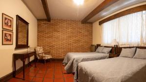 ein Hotelzimmer mit zwei Betten und einer Backsteinwand in der Unterkunft Hotel Rancho El Morillo in Saltillo