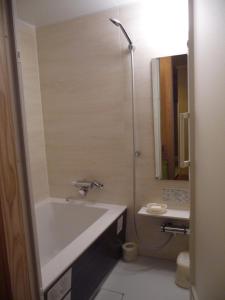 a bathroom with a bath tub and a sink at Jizokan Matsuya Ryokan in Nagano