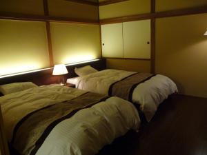 2 camas en una habitación de hotel con 2 lámparas en Jizokan Matsuya Ryokan, en Nagano