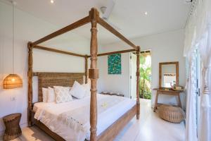 a bedroom with a wooden canopy bed in a room at Villa Santai at Sandy Bay in Nusa Lembongan