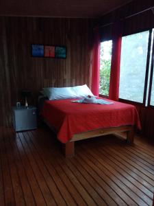 a bedroom with a bed with a red blanket at The Green Tree Lodge in Monteverde Costa Rica