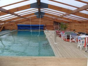 a swimming pool with a wooden roof and a swimming poolvisor at Gîte-L'Ange Blanc 20 personnes in Lignières