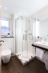 a bathroom with a shower and a toilet and a sink at Hotel & Living Am Wartturm - Hotel & Apartments in Speyer