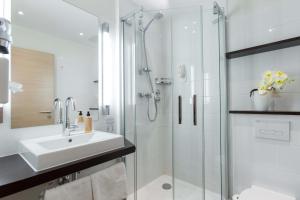 a white bathroom with a sink and a shower at Hotel & Living Am Wartturm - Hotel & Apartments in Speyer