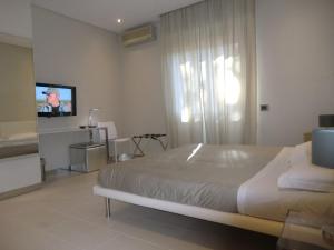 1 dormitorio con 1 cama y TV de pantalla plana en B&Beach Cagliari guest house, en Cagliari