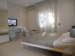 a bedroom with a bed and a flat screen tv at B&Beach Cagliari guest house in Cagliari