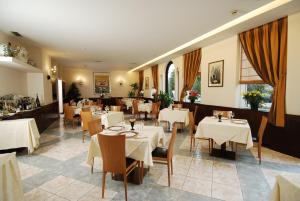 uma sala de jantar com mesas e cadeiras brancas em Park Hotel Ripaverde em Borgo San Lorenzo