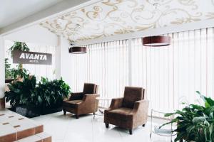 a lobby with two chairs and a table and plants at Hotel Avanta in Vladivostok