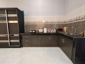 eine Küche mit schwarzen Schränken und einer Kachelwand in der Unterkunft Ku's Roomstay in Pantai Cenang
