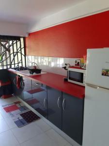 uma cozinha com paredes vermelhas e um frigorífico branco em Appartement dans Villa avec jardin et piscine pour détente et évasion em Montjoly