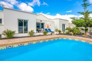 a villa with a swimming pool in front of a house at B2 Bungalow Casitas de luz in Charco del Palo