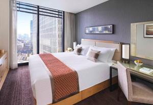 a bedroom with a large bed with a desk and a window at Oakwood Premier Tokyo in Tokyo