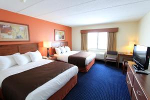 a hotel room with two beds and a flat screen tv at AmericInn by Wyndham Cedar Rapids Airport in Cedar Rapids