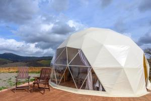 - une tente en forme de dôme blanc avec 2 chaises sur la terrasse dans l'établissement Glamping il Sole, à Civitella Marittima