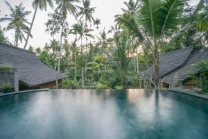 a swimming pool in front of a resort with palm trees at Sweet Orange Pondok in Ubud