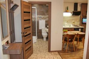 a bathroom with a toilet and a kitchen with a table at Molex Apartments 3 in Chernihiv