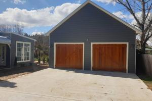 uma garagem com duas portas de garagem castanhas em The Bower@ Kings Cottage em Uralla