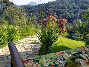 a bench in a garden with a view of a mountain at Flats vista bela com vista da montanha in Paraty