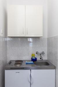 a kitchen counter with a sink and white cabinets at Apartment Rose Garden in Dubrovnik